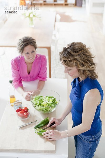 Zwei Frauen bereiten Salat in der Küche zu.