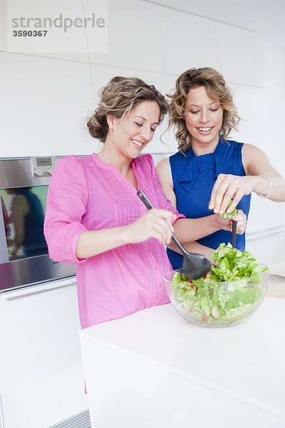 Zwei Frauen bereiten gemeinsam grünen Salat zu