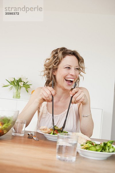 Frau mit gemischtem Salat auf dem Tisch