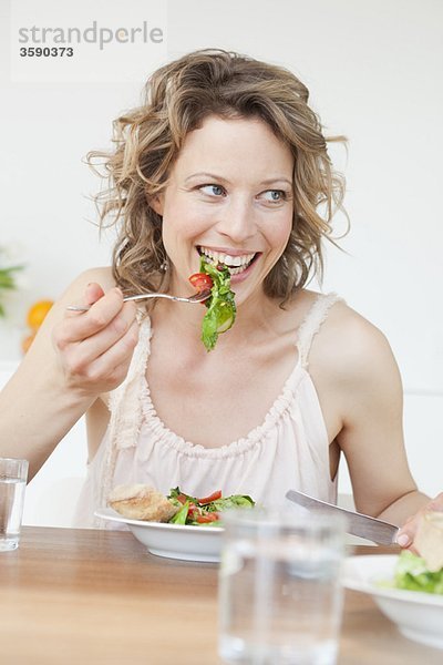 Frau isst gemischten Salat auf dem Tisch