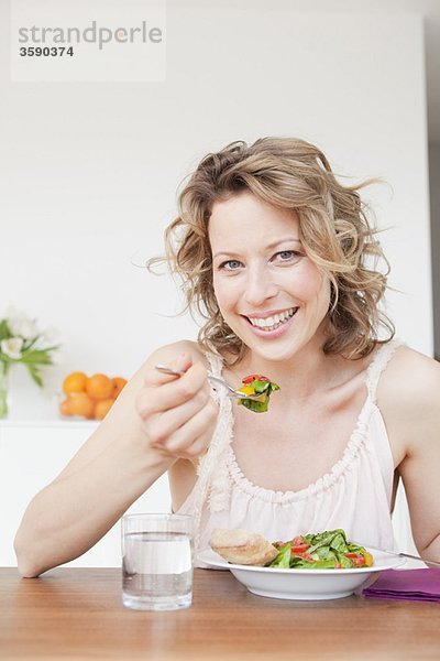 Frau isst gemischten Salat auf dem Tisch