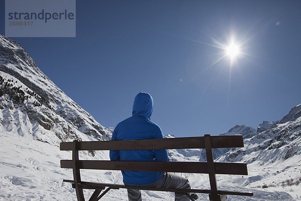 Mann vor einem Gletscher sitzend