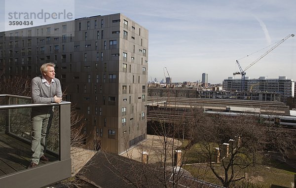 Mann steht auf dem Balkon