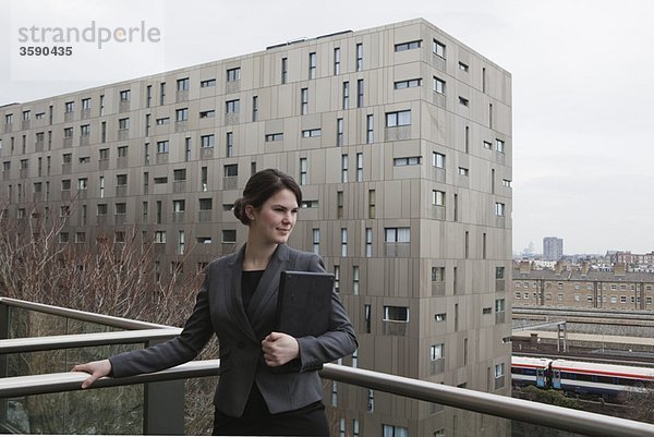 Frau stehend mit Laptop auf dem Balkon