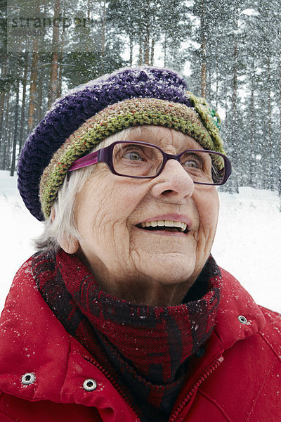 Lächelnde ältere Frau beim Schneefall