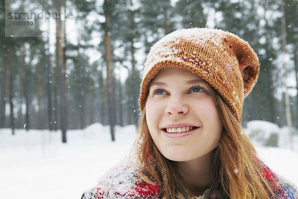 Lächelnde junge Frau beim Schneefall