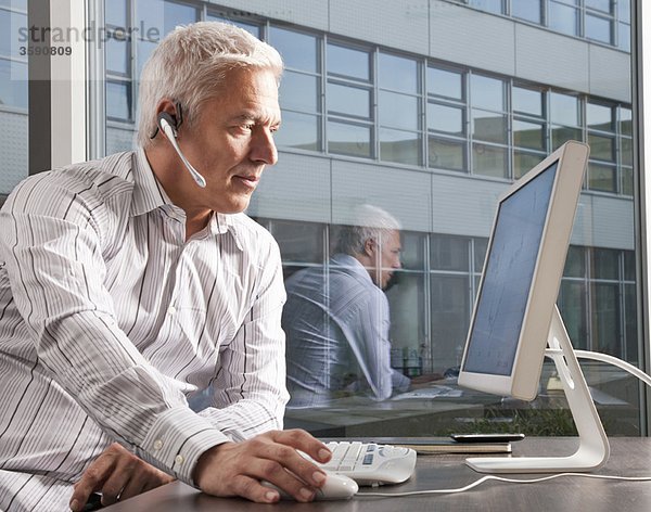 Mann mit Headset arbeitet am Computer