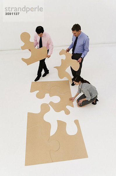 3 Geschäftsleute vervollständigen das Puzzle