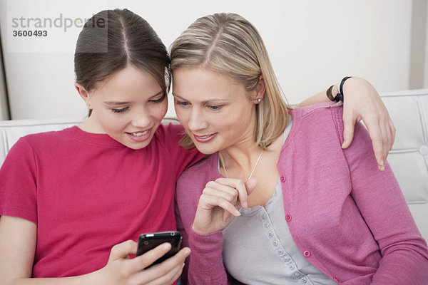 Frau und Tochter beim Lesen einer SMS auf dem Handy