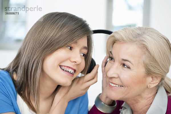 Frau mit ihrer Enkelin beim Hören von Kopfhörern