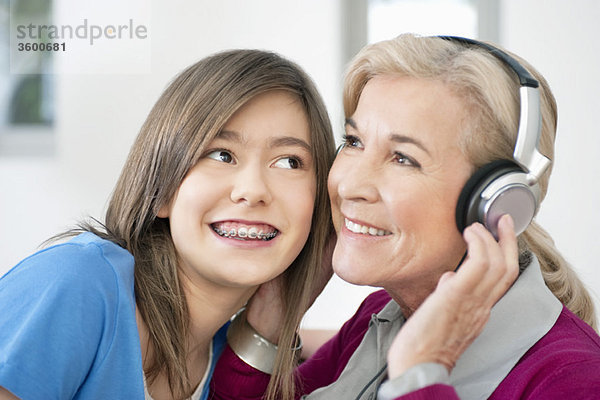 Frau mit ihrer Enkelin beim Hören von Kopfhörern