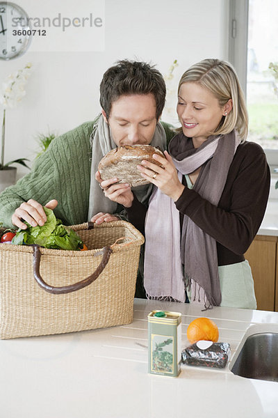 Mann riecht einen Laib Brot  seine Frau steht neben ihm.