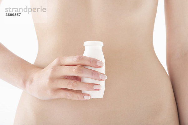 Mittelteilansicht einer Frau  die eine Flasche probiotisches Getränk in der Hand hält.