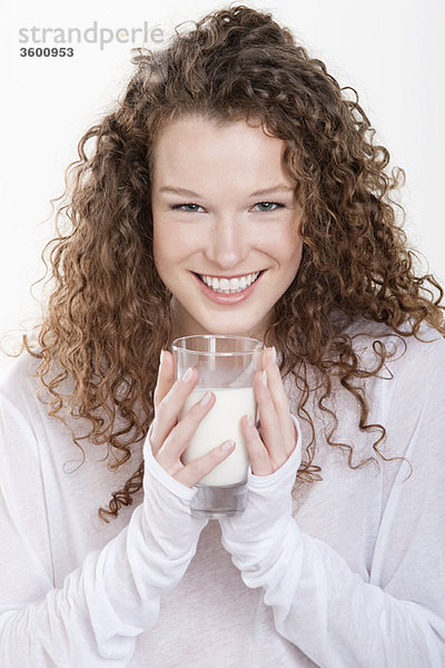 Porträt einer Frau  die ein Glas Milch hält und lächelt