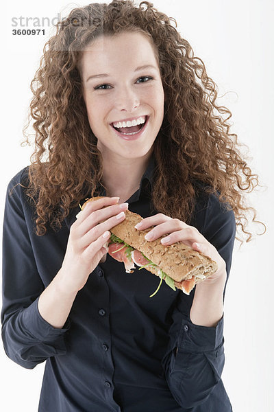 Eine Frau hält ein Sandwich und lacht.