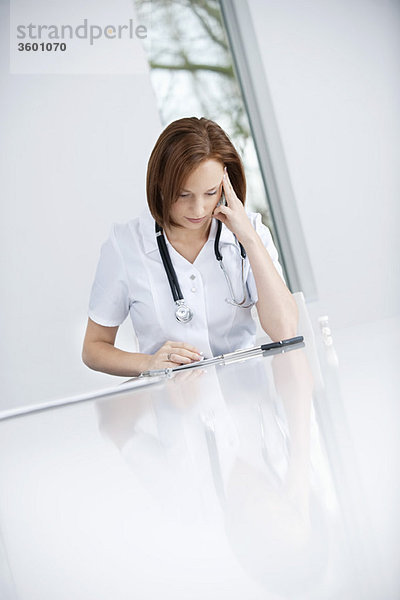 Eine Ärztin sitzt in einem Büro und sieht verärgert aus.