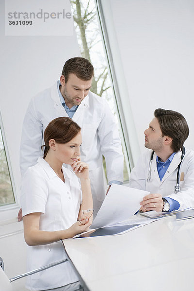 Drei Ärzte bei der Untersuchung eines medizinischen Gutachtens