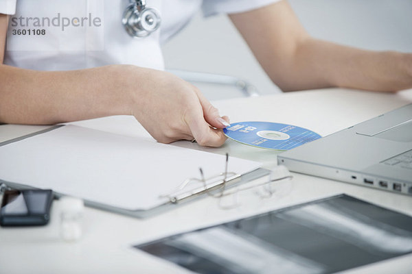 Ärztin beim Einlegen einer CD in einen Laptop