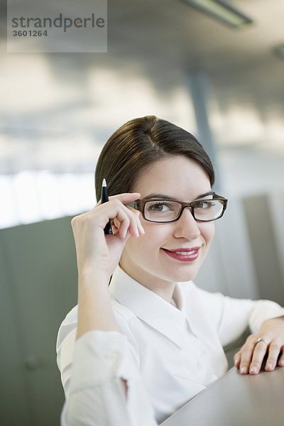 Porträt einer Geschäftsfrau  die ihre Brille anpasst und lächelt