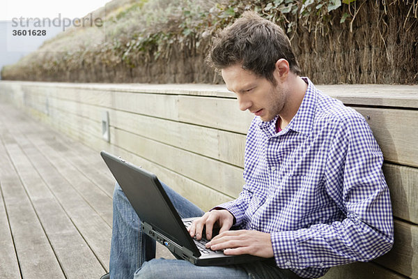 Mann mit einem Laptop auf einer Promenade