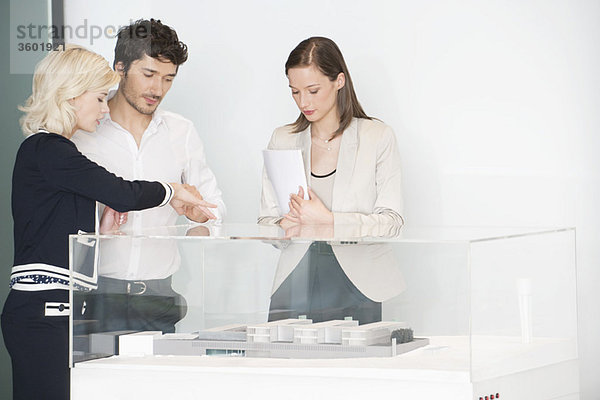 Mann mit zwei Frauen beim Betrachten eines Architekturmodells