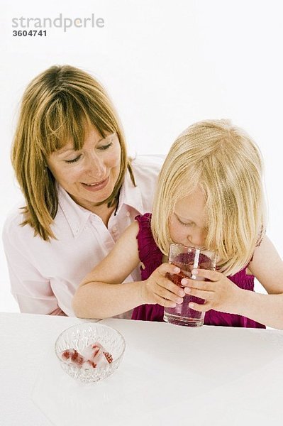 Mädchen trinkt Wasser mit Himbeereiswürfeln