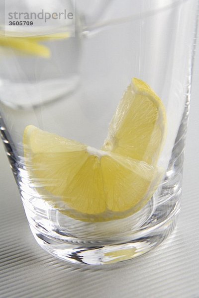 Wasserglas mit Zitronenschnitzen (Nahaufnahme)