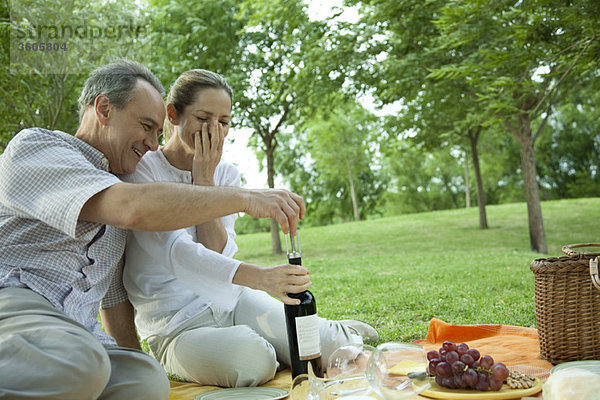 Erwachsenes Paar beim Picknick im Freien  Flasche Wein öffnen