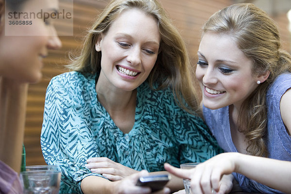 Junge Frau zeigt Freunden ihr Handy