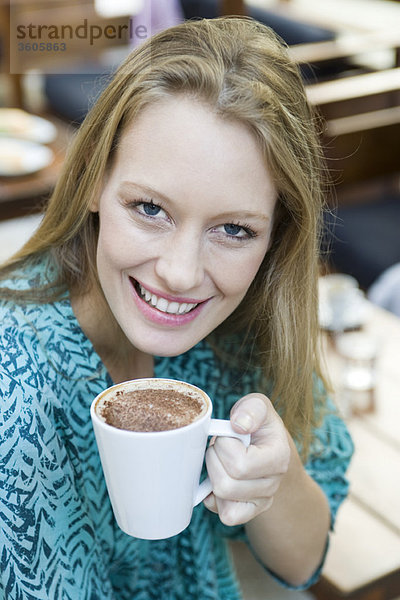 Junge Frau genießt Tasse Cappuccino  Portrait