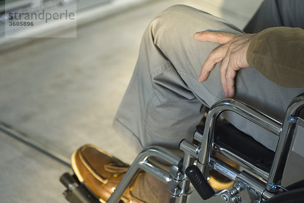 Behinderte Person im Rollstuhl im Freien sitzend