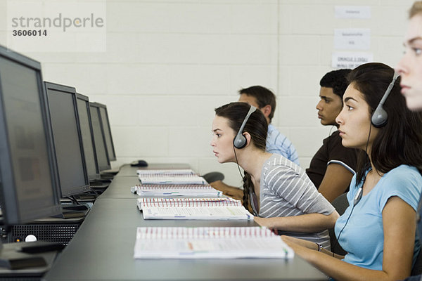 Studenten  die im Computerlabor studieren  einer lehnt sich nach vorne  um den Bildschirm zu sehen.