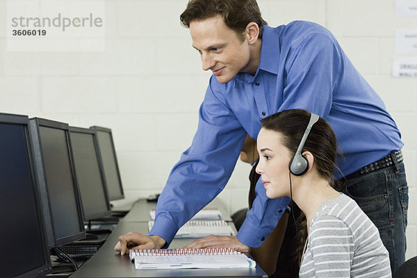Lehrer assistiert Schüler im Computerlabor