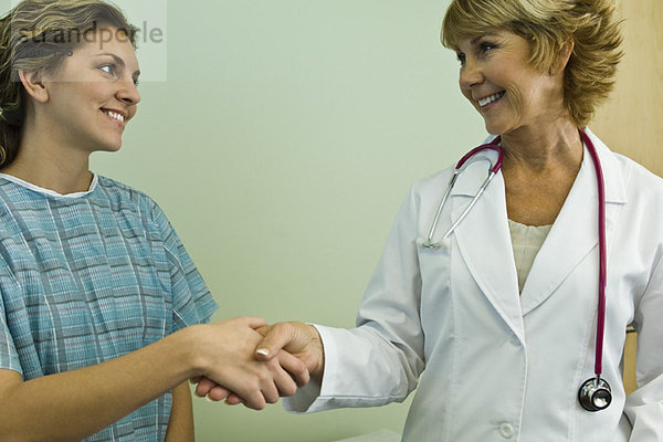 Arzt schüttelt dem Patienten die Hand  beide lächelnd