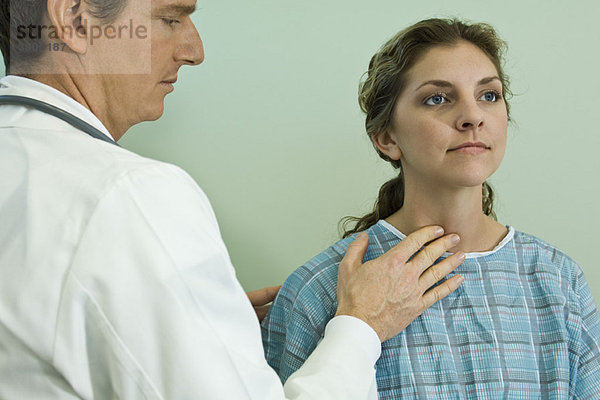 Arzt untersucht die Halsdrüsen des Patienten