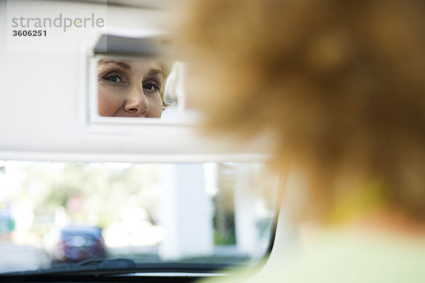 Frau im Auto schaut sich selbst im Visier-Eitelkeitsspiegel an