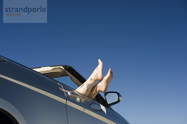 Entspannen im geparkten Cabriolet  Füße auf der Tür liegend