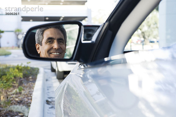 Mann sitzt im geparkten Auto  Spiegelung im Seitenspiegel