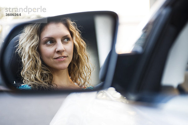 Junge Frau beim Autofahren  Spiegelung im Seitenspiegel