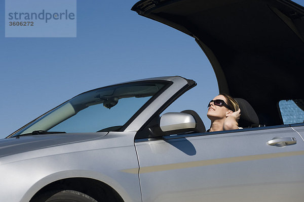 Frau legt Cabrioverdeck ab und bereitet sich auf die Fahrt am Sommertag vor