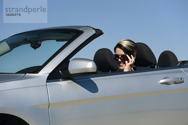 Frau im Cabrio  Sonnenbrille absenken  um in die Kamera zu schauen
