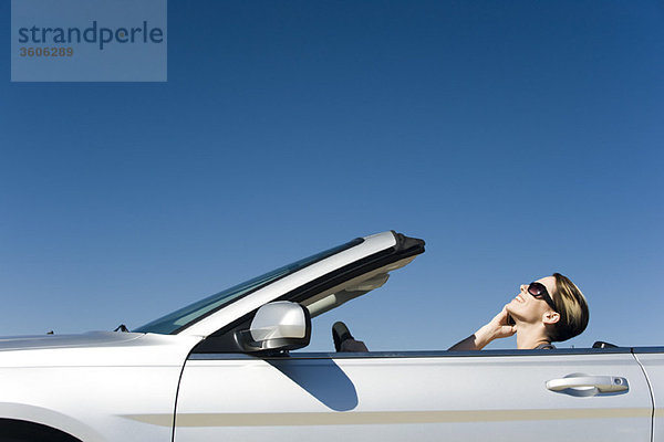 Frau spricht auf dem Handy während der Fahrt Cabriolet