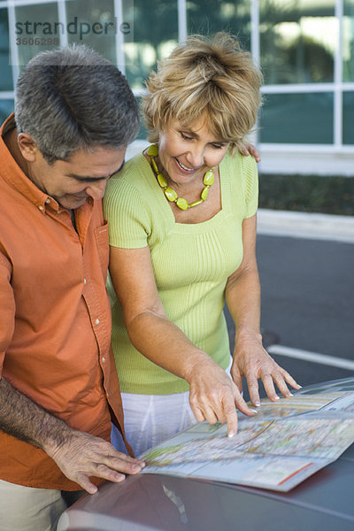 Ein reifes Paar schaut sich gemeinsam die Straßenkarte an und bespricht die Route für die Reise.