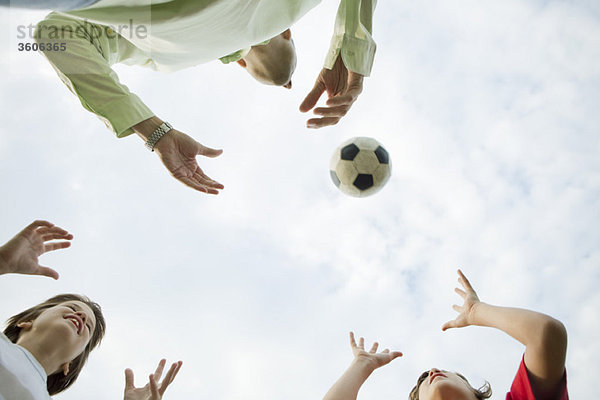 Vater und Söhne spielen mit dem Fußball  Blick in den niedrigen Winkel