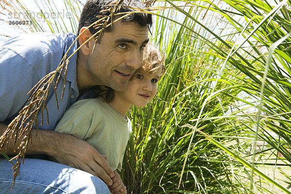 Vater und Sohn verstecken sich im hohen Gras.