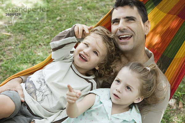 Vater und zwei Kinder entspannen gemeinsam in der Hängematte