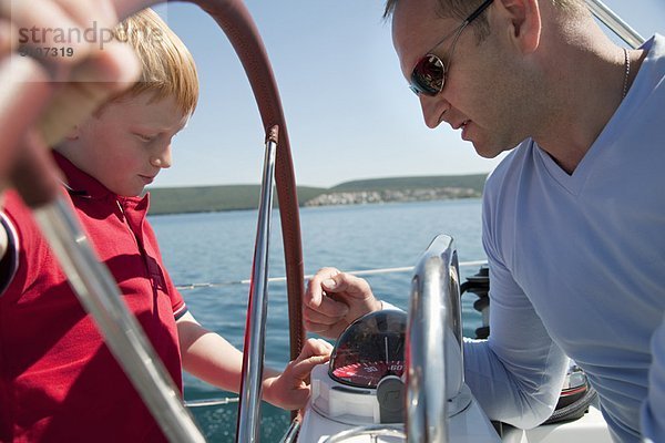 Mann erklärt Jungen-Kompass auf der Yacht