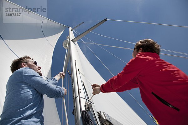 Zwei Männer ziehen Seile auf der Yacht