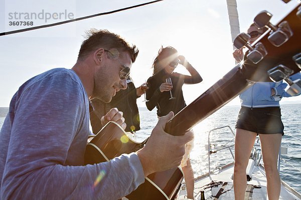 Freunde tanzen mit Gitarre auf der Yacht