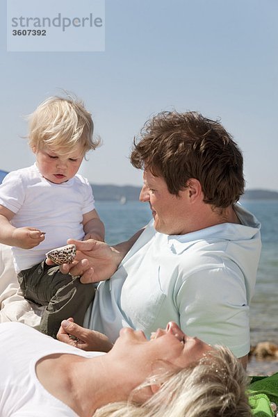 Familie am Strand mit Blick auf Muscheln